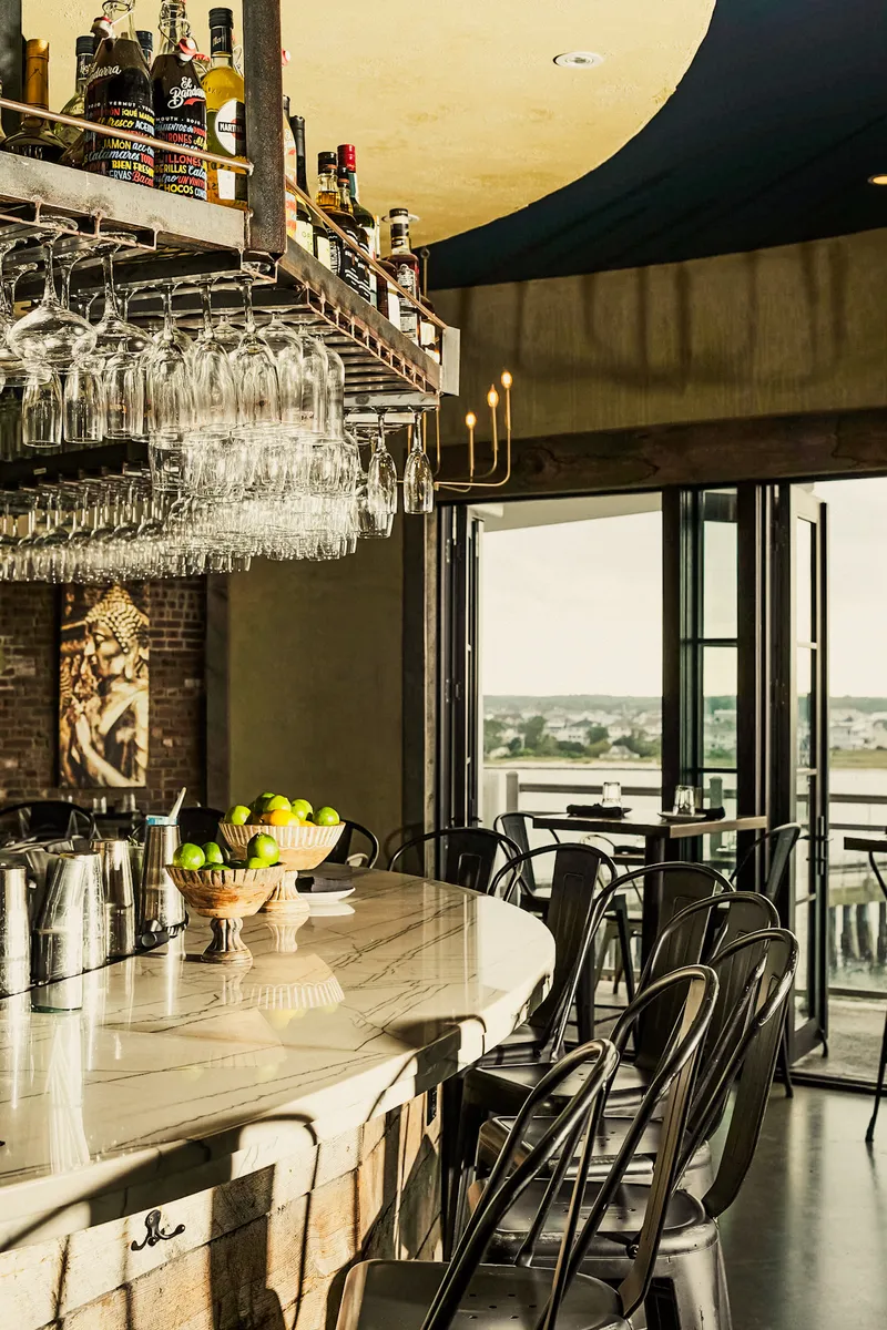 The bar lined with glassware beside bay windows